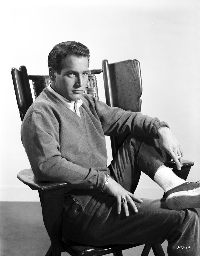 Black and white photo print of Paul Newman sitting in a chair, dressed in a formal outfit.