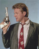 David Rasche photo print holding a pistol in black suit with red tie