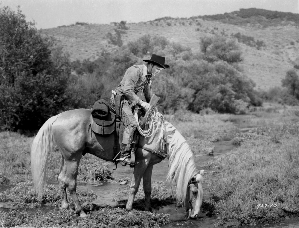 Roy Rogers riding on a horse eating grass photo print