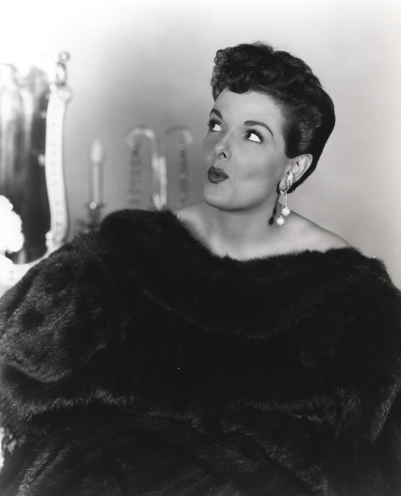 Jane Russell portrait in black fur coat and pearl earrings looking up
