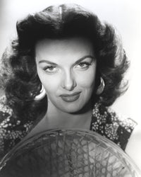 Jane Russell close-up portrait in black floral dress with straw hat on white background.