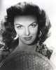 Jane Russell close-up portrait in black floral dress with straw hat on white background.