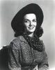 Jane Russell portrait in long sleeve shirt and cowboy hat against white background.