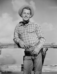 Alan Ladd leaning on a wooden fence in cowboy outfit photo print.