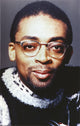 Close-up portrait of Spike Lee smiling with eyeglasses.