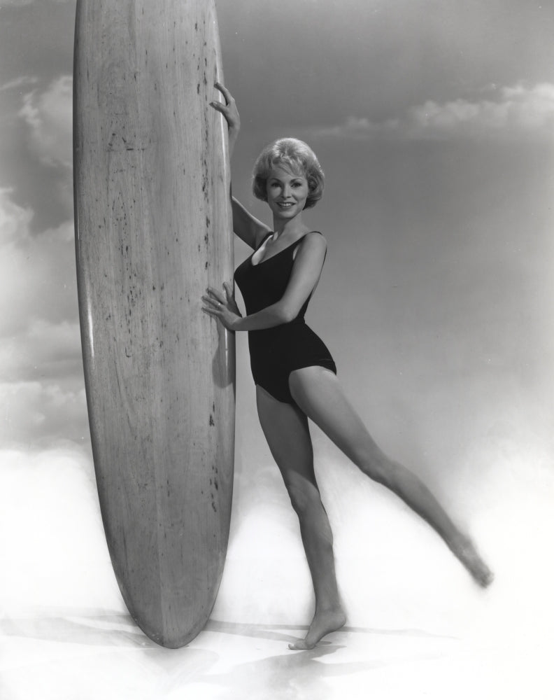Janet Leigh posing in a black linen swimsuit holding a surfboard photo print