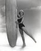 Janet Leigh posing in a black linen swimsuit holding a surfboard photo print