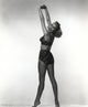 Janet Leigh in black two-piece photo print, arms stretched up.
