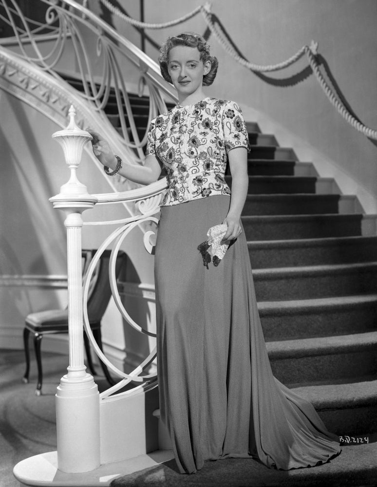 Bette Davis photo print standing beside a white staircase holding a handkerchief.