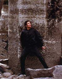 Benicio Del Toro leaning on wall in black coat photo print.