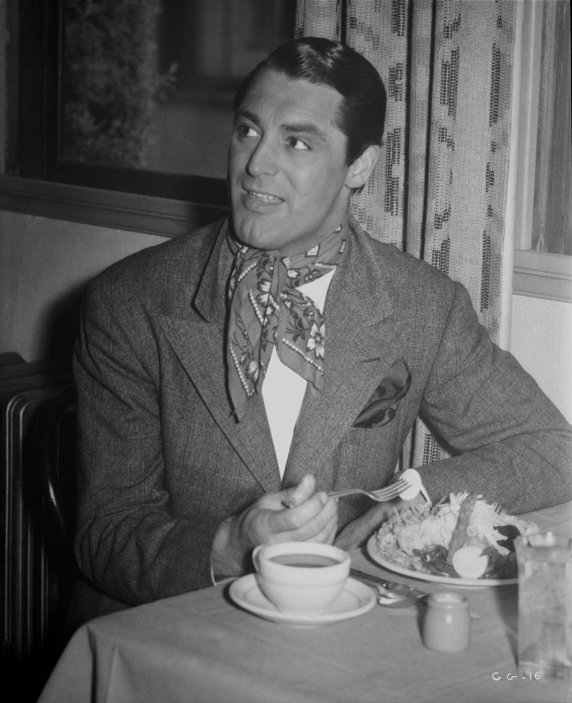 Cary Grant dining photo print in scarf and jacket, classic Hollywood style.
