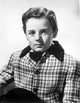 Freddie Bartholomew seated on a side boat wearing a white suit - Photo Print
