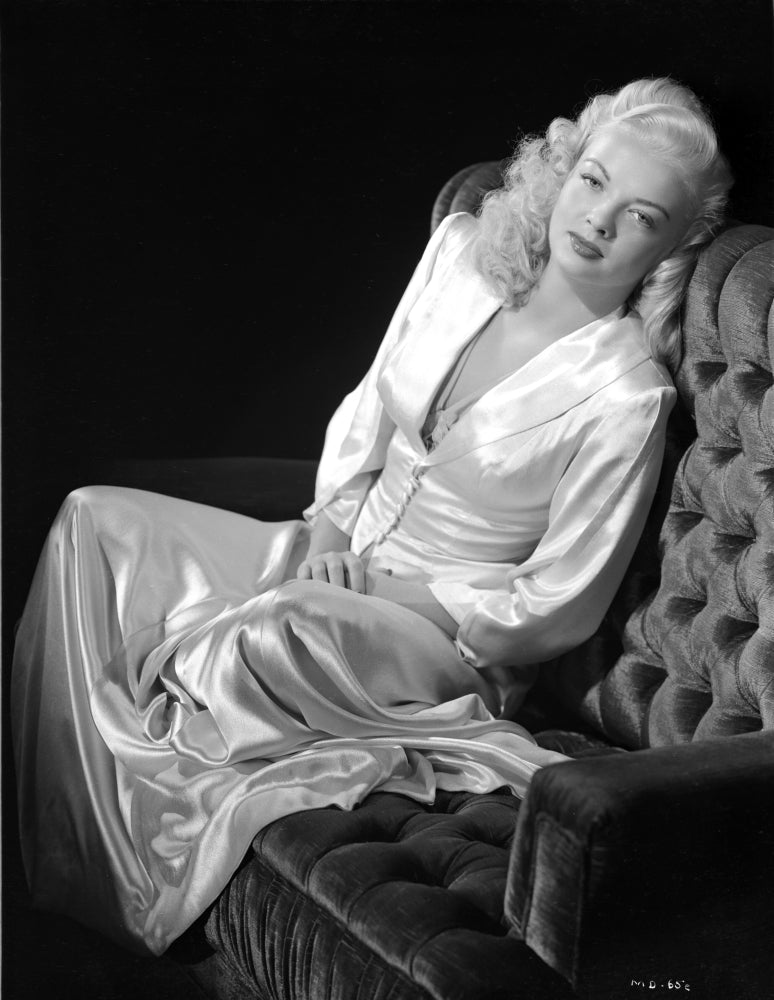 Myrna Dell sitting on couch in silk dress black and white photo print