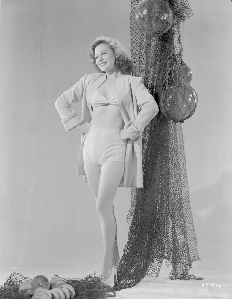 Susan Hayward smiling in trench coat and white bikini photo print.