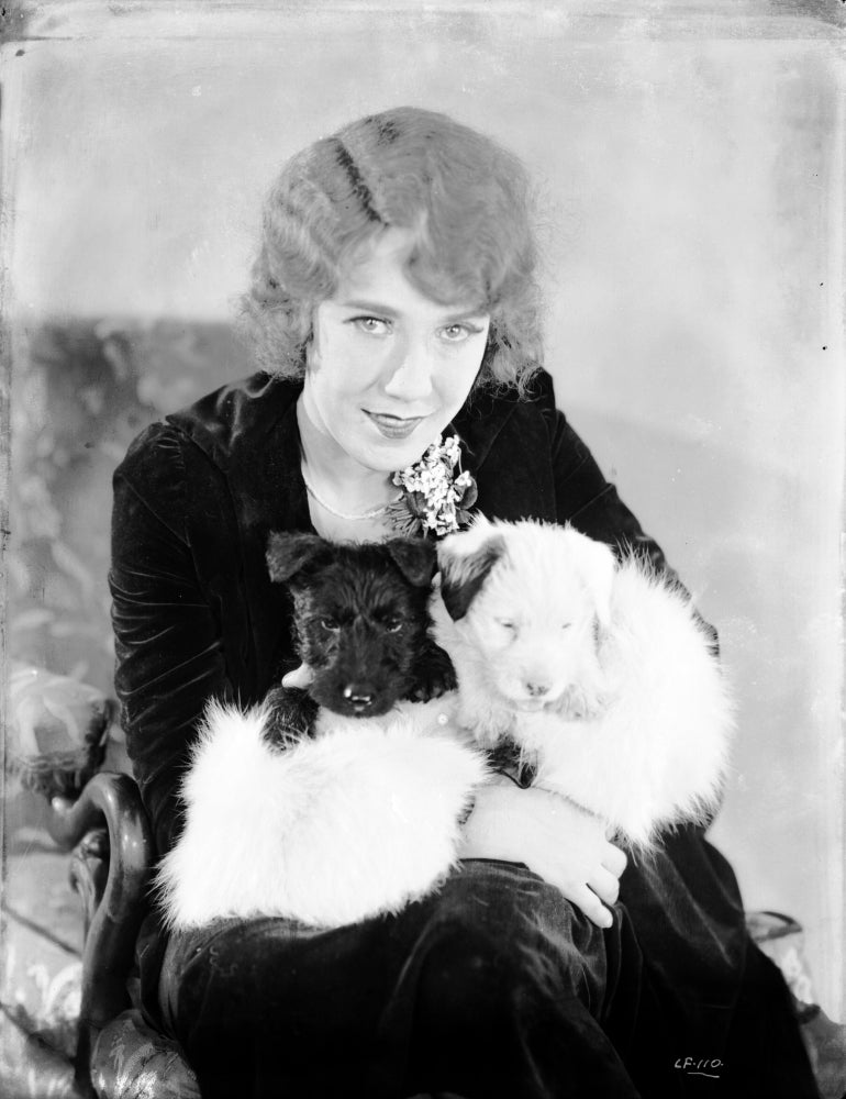 Louise Fazedna in black dress carrying a puppy photo print