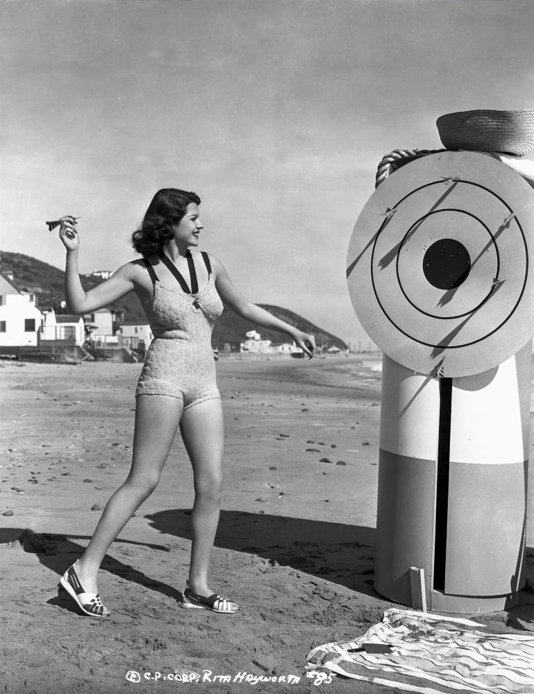 Rita Hayworth photo print in a swimming suit playing dart game.