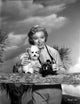Greer Garson photo print, posed wearing silk top holding a camera and a dog.