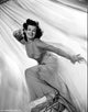 Barbara Hale in a lace dress posing elegantly on a chair.