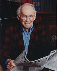 Portrait of Barnard Hughes holding a newspaper photo print.