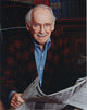 Portrait of Barnard Hughes holding a newspaper photo print.
