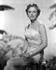 Virginia Huston seated in a midriff top and short skirt photo print.