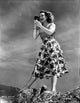 Betty Hutton on a printed skirt holding a camera, photo print.
