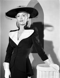 Carole Landis lying on a printed couch answering a phone in a vintage photo print.