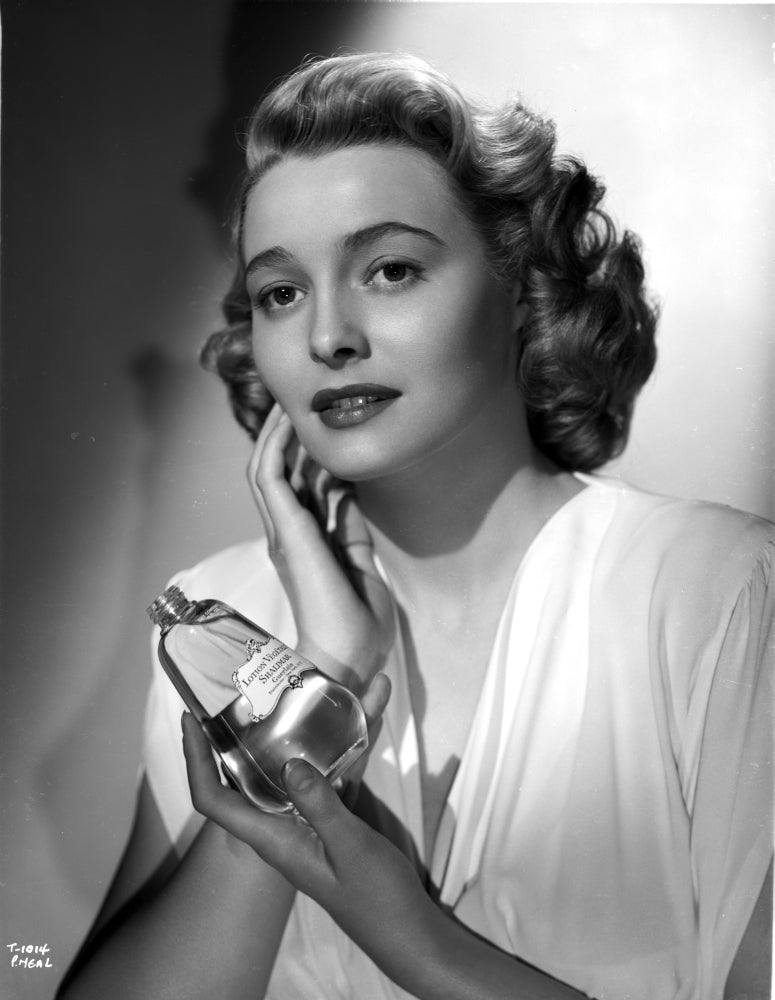 Patricia Neal holding perfume in elegant dress photo print.