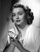 Patricia Neal holding perfume in elegant dress photo print.