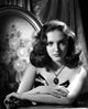Portrait photo print of Joan Newton leaning on a table in a strapless black dress.