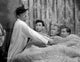 Smuggler's Cove photo print featuring three men lying on a bed in a movie scene.