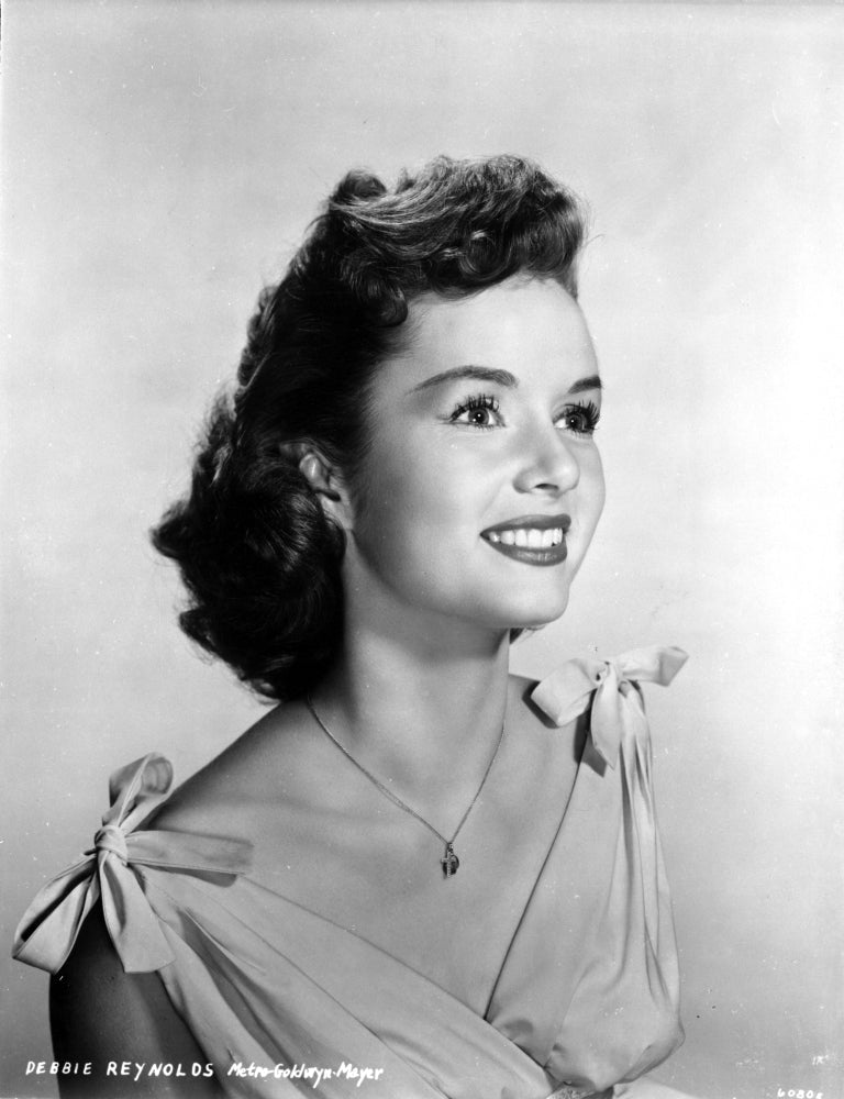 Debbie Reynolds smiling in a white dress with ribbon shoulder photo print.