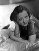 Sylvia Sidney lying on silk bed linens in shiny blouse photo print.
