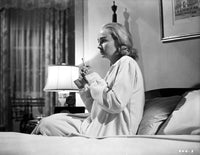 Jean Simmons seated on the bed in a long sleeve sleep dress photo print.
