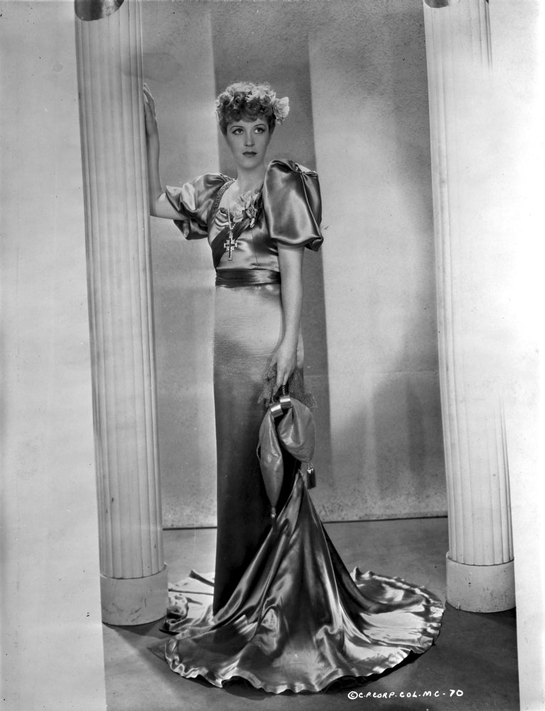 Betty Stockfeld standing in an elegant glossy gown photo print.