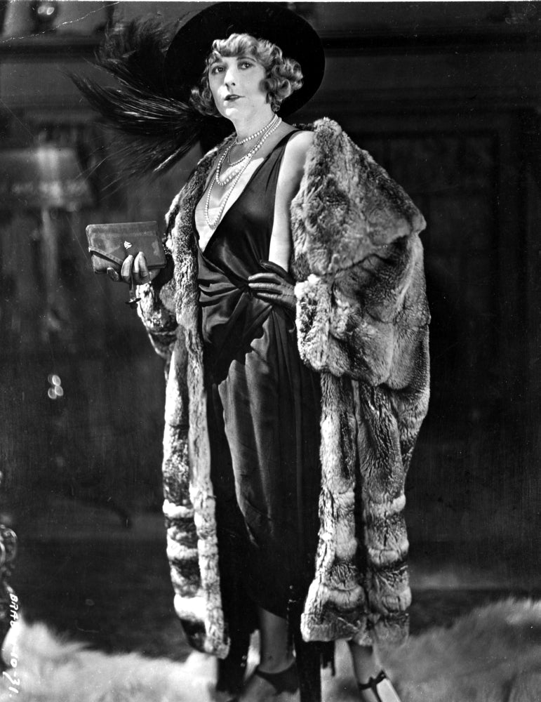 Elegant portrait photo print of a pearl white cast member in a black dress and fur coat.