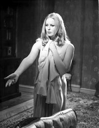 Veronica Carlson standing with arm raised and clutching a jacket photo print.