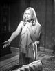 Veronica Carlson standing with arm raised and clutching a jacket photo print.