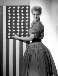 Jan Sterling photo print in velvet dress, touching flag.