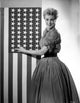 Jan Sterling photo print in velvet dress, touching flag.