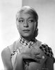 Carol Channing photo print in a printed blouse with hand on chest.