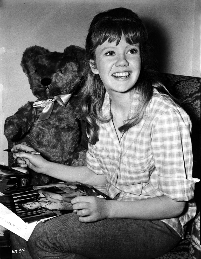 Photo print of Hayley Mills wearing a checkered polo shirt with stuffed toy.