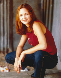 Portrait photo print of Jordana Spiro in a red sleeveless shirt and denim pants.