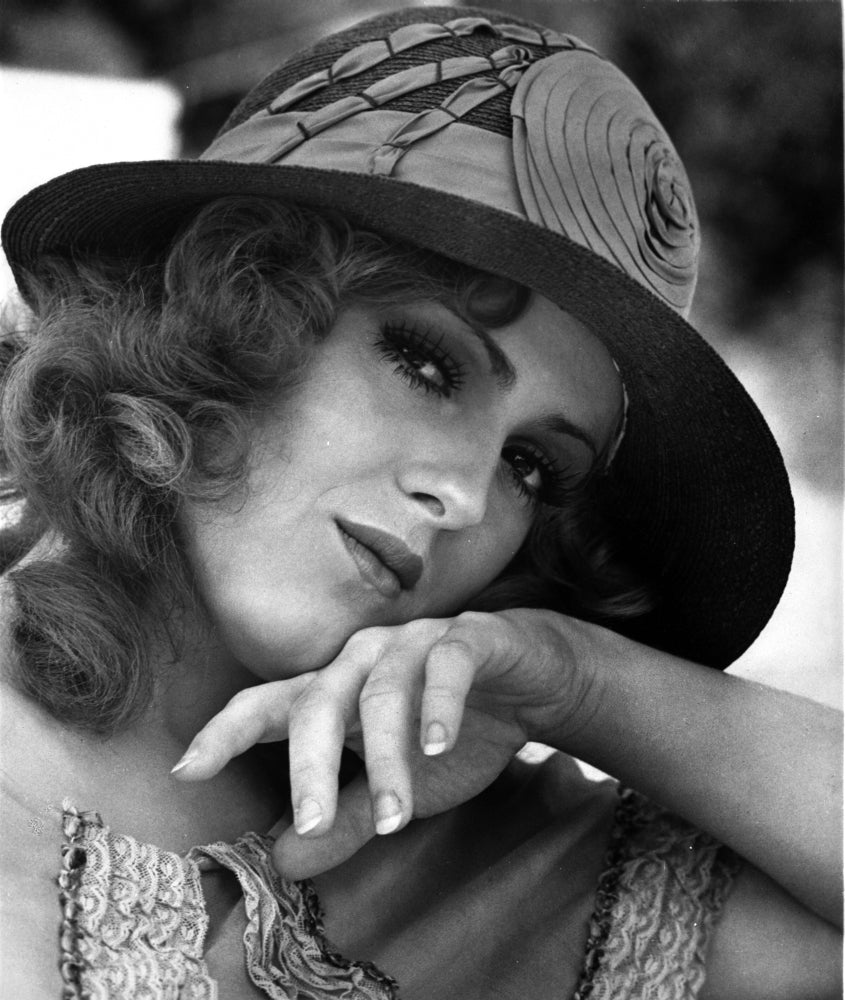 Close-up portrait of Bernadette Peters in a round wool hat and white blouse.