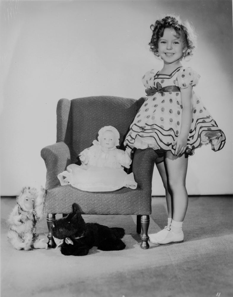 Shirley Temple standing with stuffed animals photo print