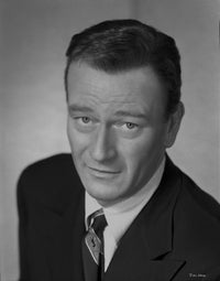 John Wayne looking at the camera in a black suit and tie photo print
