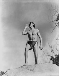 Johnny Weissmuller shouting from a big rock in a movie scene photo print.