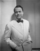 Orson Welles photo print in tuxedo with hands in pocket.