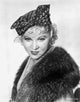 Mae West smiling in a black fur coat and polka dot hat photo print.