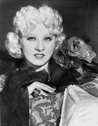 Mae West posed in a black dress photo print showcasing her short curly hairstyle.